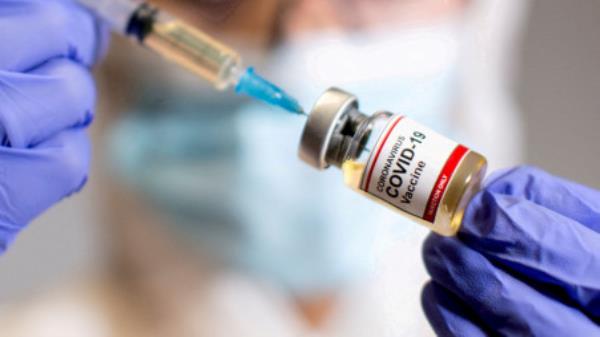 A woman holds a small bottle labelled with a &quot;Coro<em></em>navirus COVID-19 Vaccine&quot; sticker and a medical syringe in this illustration taken October 30, 2020. REUTERS/Dado Ruvic/File Photo